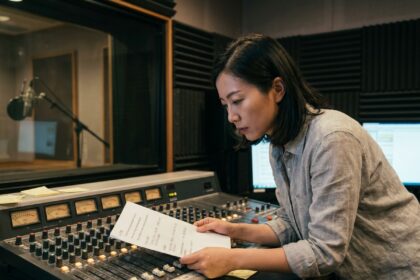 Ingénieure audio chinoise analysant un script bilingue français-mandarin dans un studio de radio professionnel